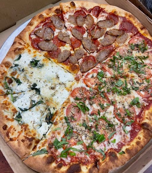 Pizza with four different toppings and fresh basil
